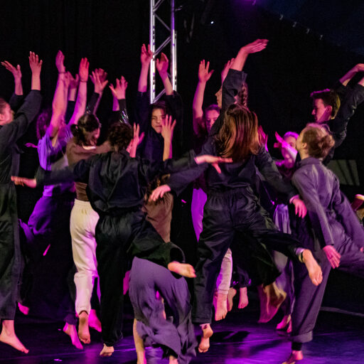 Gruppe von Jugendlichen, dunkel gekleidet auf einer Bühne