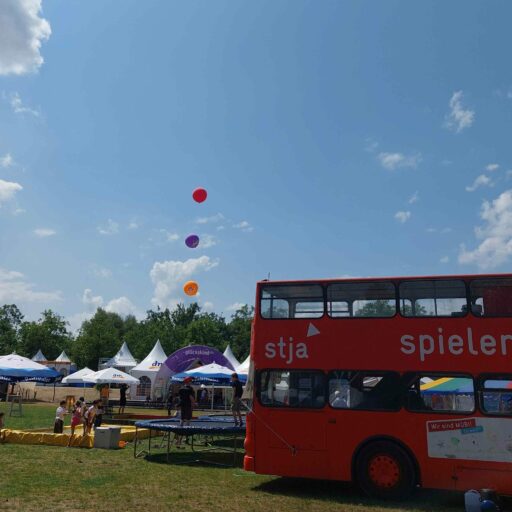 Der Mobi-Bus auf einer Wiese mit Veranstaltungspavillons