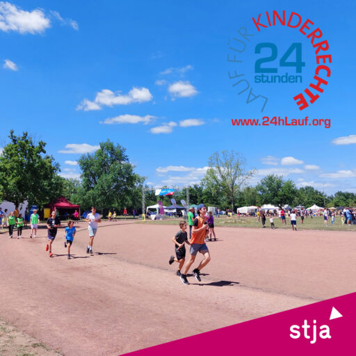 Zu sehen ist ein Sportplatz mit einer Laufbahn, darauf laufende Kinder, im Hintergrund Menschen und Zelte