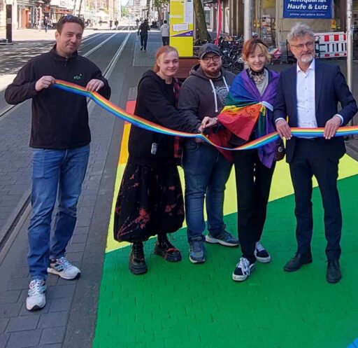 5 Menschen, darunter Oberbürgermeister Frank Mentrup, halten ein regenbogenfarbites Band. Sie stehen auf der auf den Boden aufgemalten Regenbogenfläche