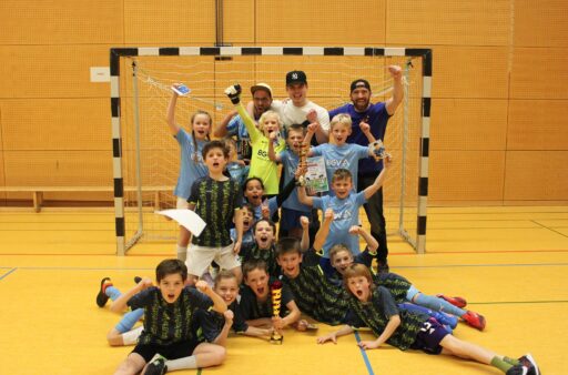 Die Gewinnermannschaften mit Trainern jubelnd vor einem Fußballtor