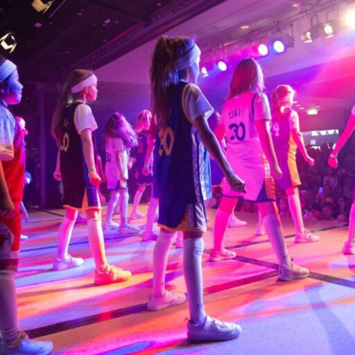 Blick von hinten auf die Bühne mit jugendlichen Mädchen, die vor Publikum tanzen