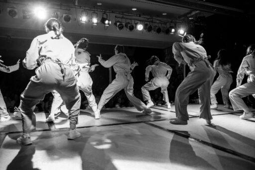 Blick von hinten auf Tanzgruppe in Aktion vor Publikum