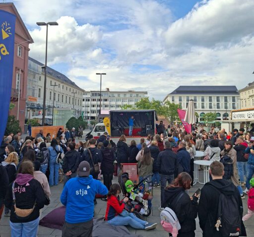 Auf dem Karlsruher Marktplatz stehen viele Jugendliche vor einem Wagen mit Bühne.