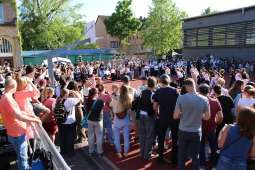 Viele Erwachsene, Jugendliche und Kinder stehen im Kreis um eine Tanzgruppe junger Mädchen