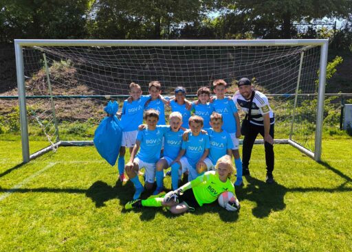 Gruppenfoto des Jungen-Fußballteams mit Trainer vor einem Tor