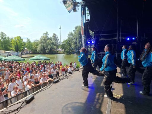 Tanzgruppe mit weiblichen Jugendlichen auf der Bühne, davor begeistertes Publikum.