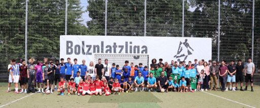 Gruppenfoto mit vielen Fußballteams von Kindern und Jugendlichen vor einem großen Banner mit der Aufschrift "Bolzplatzliga"